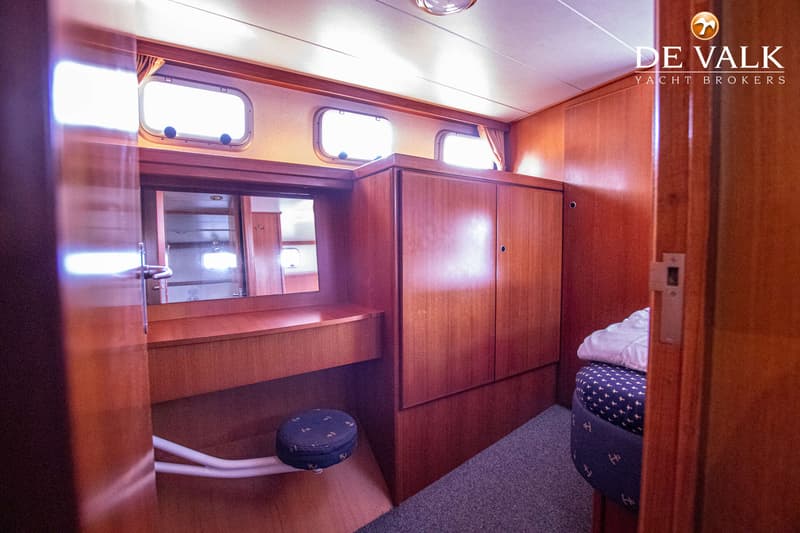 Een houten kajuit met een spiegel, patrijspoorten, een krukje en een bed met een blauw dekbed. — Pedro Marin 30