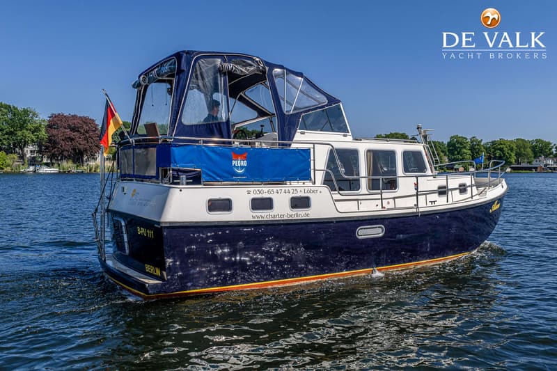 Een donkerblauwe motorboot met een witte opbouw en een blauwe kap vaart op helder water. — Pedro Marin 30