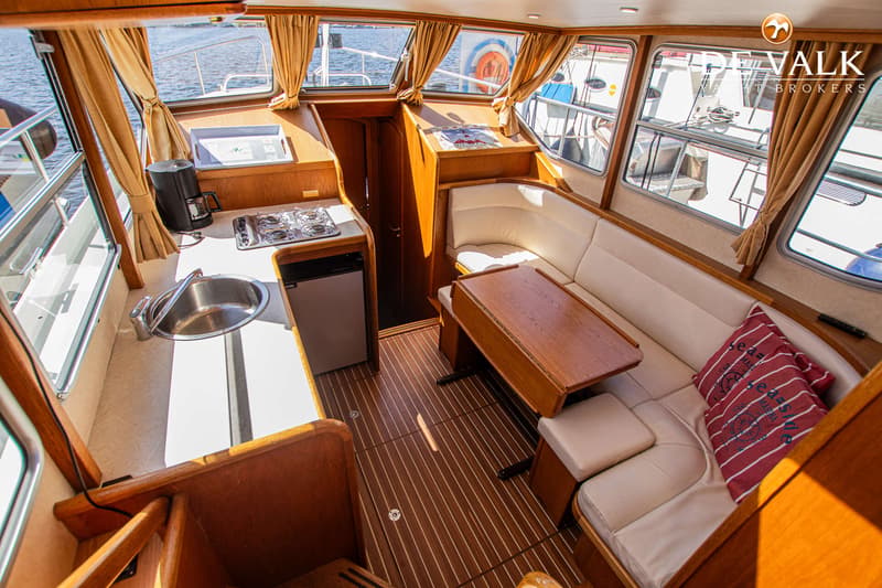 De foto toont het interieur van een boot met een kombuis, zithoek en houten accenten. — Gruno 36 Classic