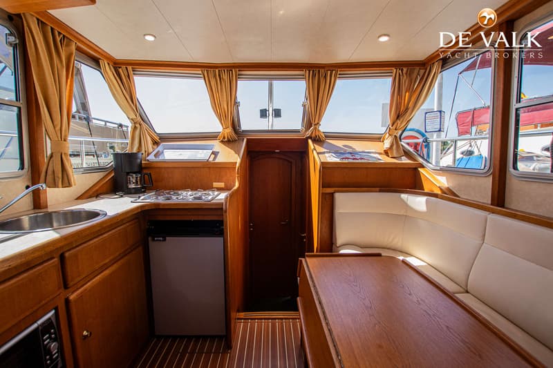 De foto toont het interieur van een boot met een kombuis, zithoek en houten afwerking. — Gruno 36 Classic