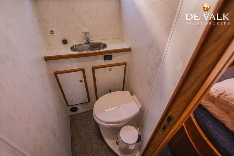 Een kleine badkamer met een toilet, een wastafel en twee opbergkastjes.