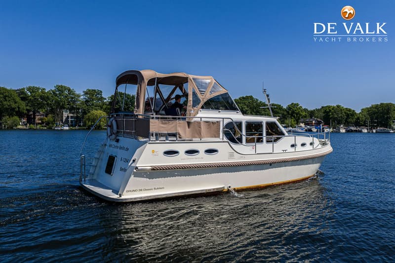 Een witte motorboot met een beige cabriokap vaart op een zonnige dag over blauw water. — Gruno 36 Classic