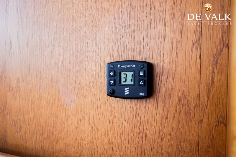 Een zwart Eberspächer bedieningspaneel met een digitaal display dat '31' toont, is gemonteerd op een houten wand.