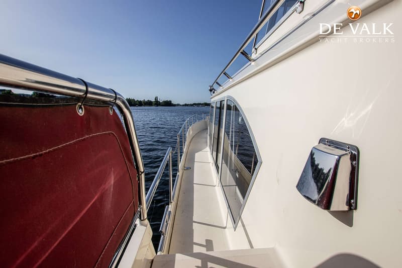 Een zijaanzicht van een boot met een rode afdekking, een gangboord, ramen en een chromen ventilatiekap. — Linskens Catfish 46