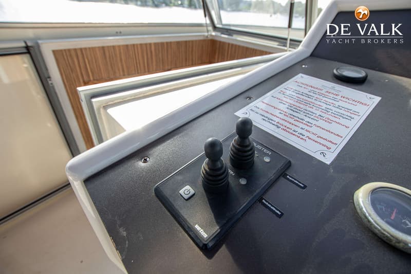 Een detailfoto van een bedieningspaneel met twee joysticks, een aan/uit-knop en een waarschuwingssticker.