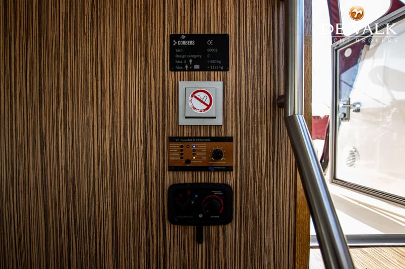 Een houten wand met een typeplaatje, een verbodsbord, een VE.Bus Multi Control paneel en een Gembles bedieningspaneel.