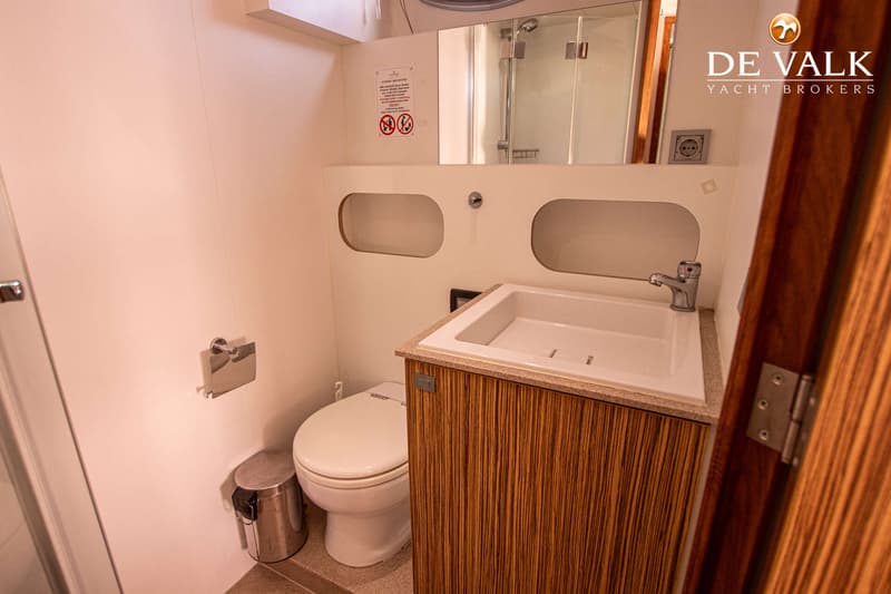 Een badkamer met een toilet, een wastafel met kraan, een spiegel en een douchecabine.