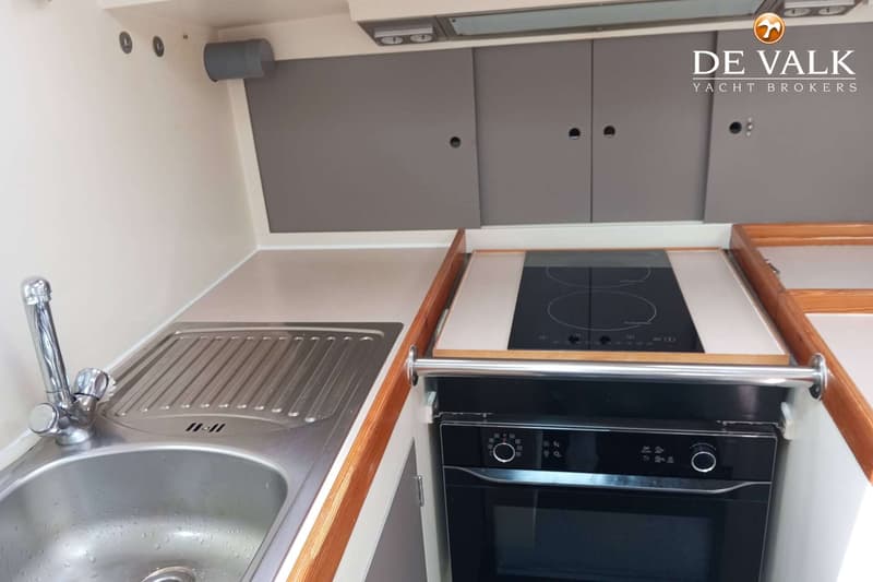Een bootkeuken met een roestvrijstalen spoelbak, een inductiekookplaat en een ingebouwde oven.
