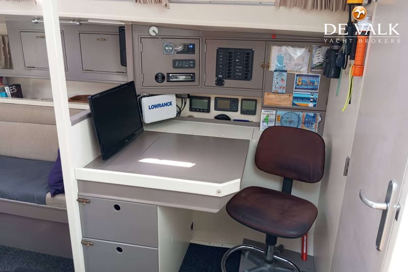 Een navigatiehoek met een bureau, een bureaustoel, diverse navigatie-instrumenten en een Lowrance-tas.