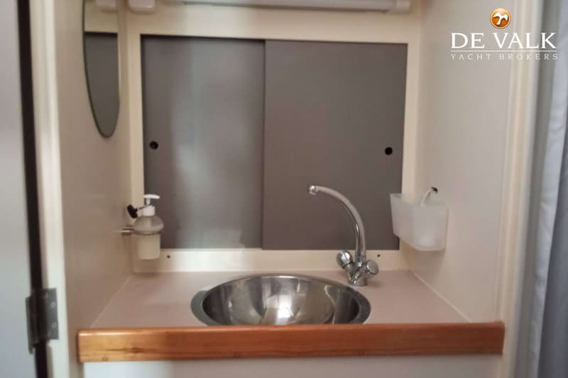 Een wastafel met kraan, een spiegel, een zeepdispenser en een opbergbakje zijn zichtbaar in een kajuit. — Van de Stadt 48