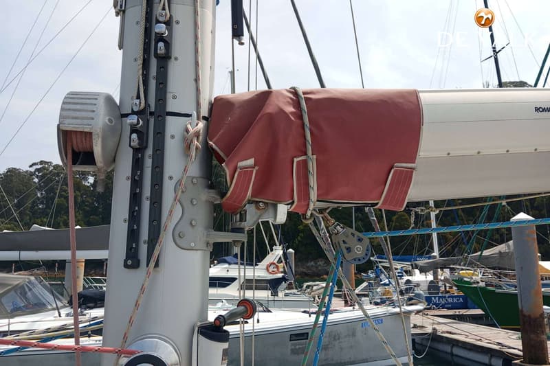 Een mast van een zeilboot met een deels rood afgedekt grootzeil, een lier en diverse lijnen. — Van de Stadt 48
