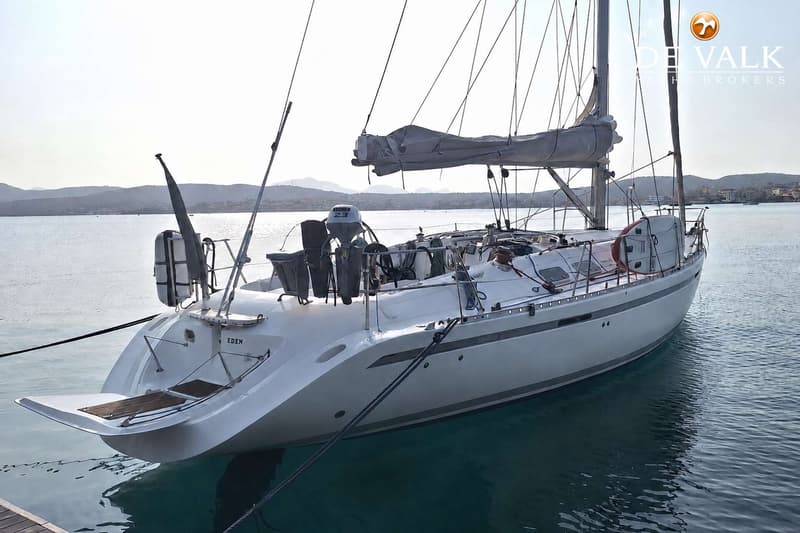 Een witte zeilboot met de naam "EDEN" ligt aangemeerd in helder water, met bergen op de achtergrond. — Beneteau First 45f5