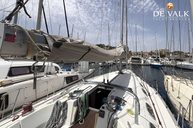 Een witte zeilboot ligt in een jachthaven met andere boten en gebouwen op de achtergrond. — Beneteau First 45f5