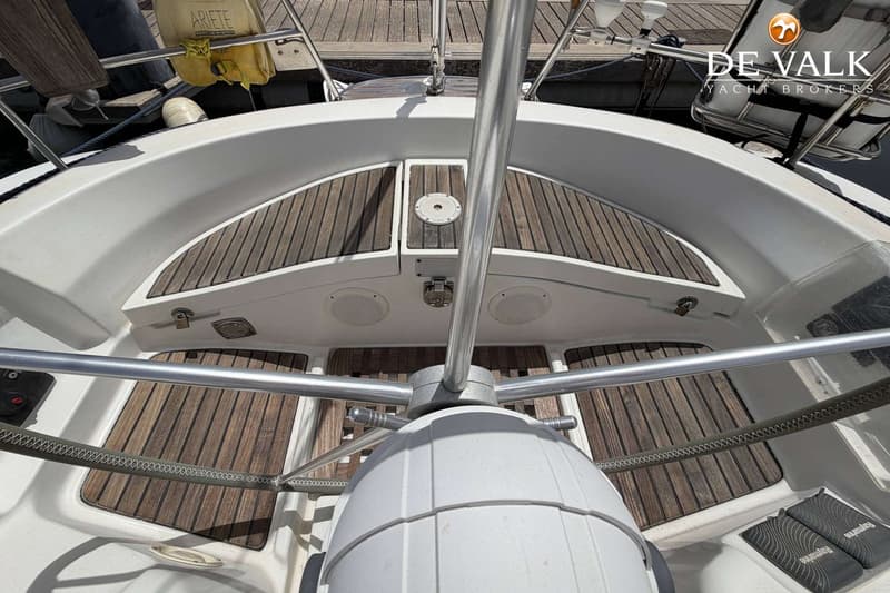 Een bovenaanzicht van de kuip van een boot met een stuurwiel, teakhouten vloer en witte zijkanten. — Beneteau First 45f5