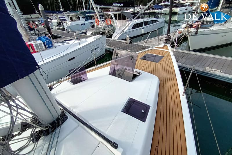 Een bovenaanzicht van een zeilboot met een houten dek en witte opbouw, liggend in een jachthaven. — Hanse 415