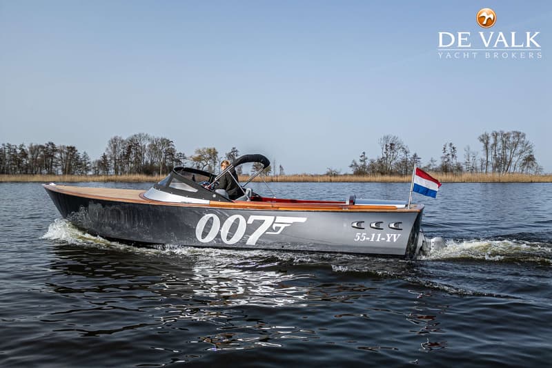 Een donkergrijze boot met "007" en een pistoollogo op de zijkant vaart op het water. — Custom Aluminium Cruiser