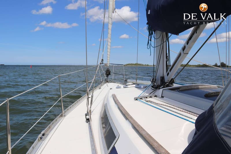 Een zeilboot vaart op open water met een blauwe lucht en enkele wolken, gezien vanaf het dek. — Beneteau First 405