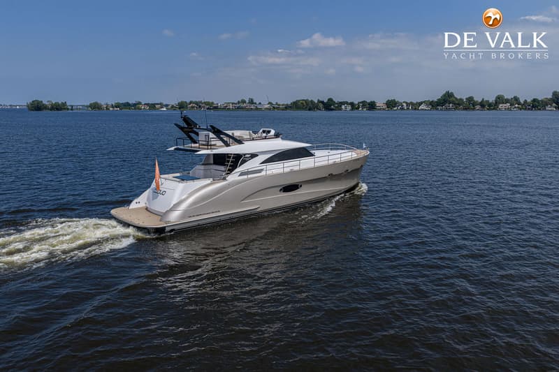 Een zilverkleurige motorboot met de naam "CLOUD" vaart over rustig water onder een helderblauwe hemel.