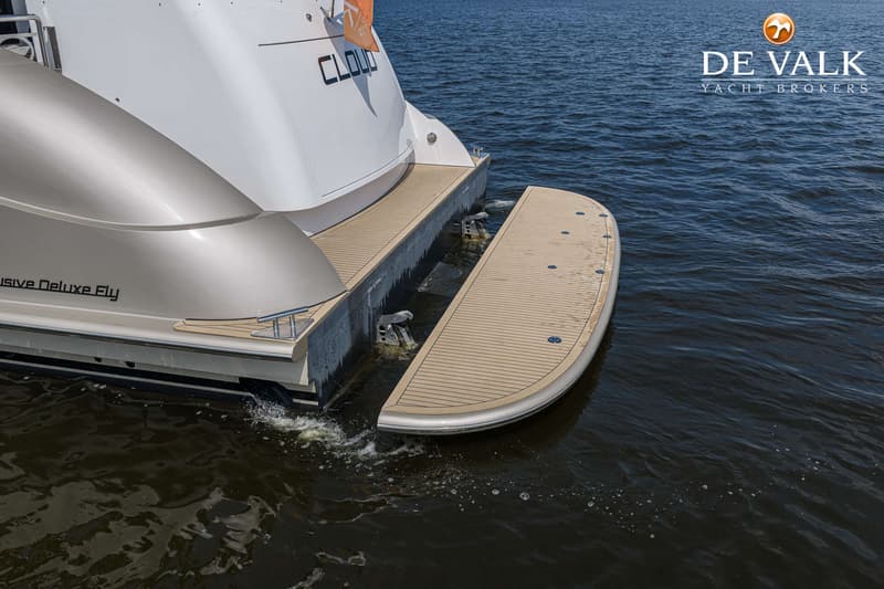 De achterkant van een witte boot met een teakhouten zwemplateau dat deels in het water ligt, met de naam "CLOUD" zichtbaar.