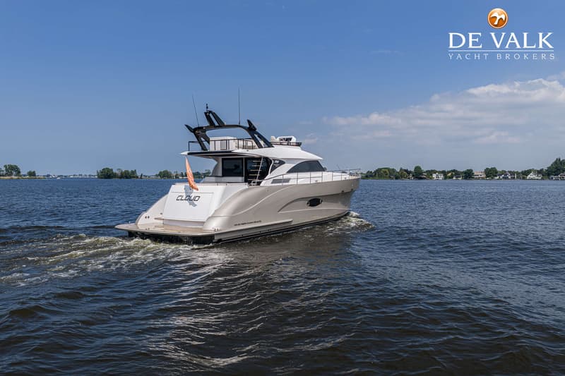 Een witte motorboot met de naam "CLOUD" vaart over rustig water, met een oranje vlag aan de achtersteven.