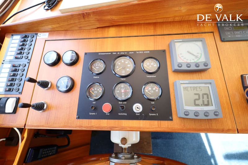 Een close-up van een houten dashboard met diverse meters, schakelaars en twee digitale displays.
