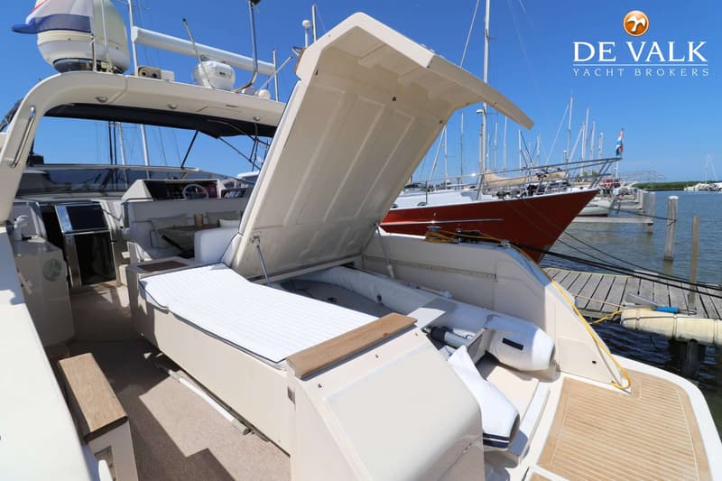 Een open luik aan de achterzijde van een boot onthult een opblaasbare bijboot, met een ligbed ernaast. — Riva 60 Bahamas