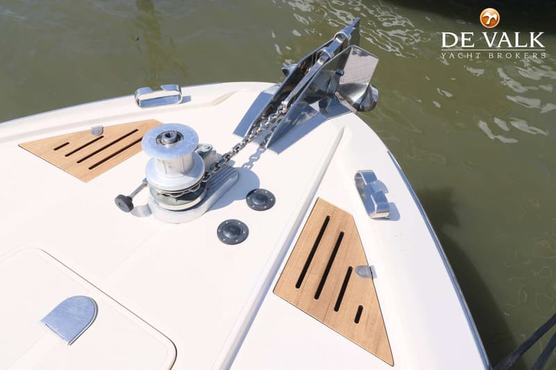 De foto toont de boeg van een boot met een anker, ankerlier, ketting en houten dekdelen. — Riva 60 Bahamas