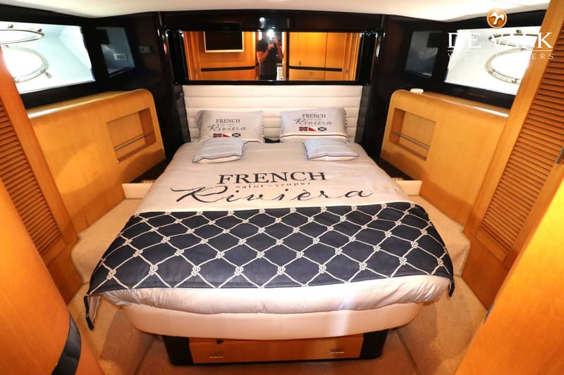 Een slaapkamer in een boot met een groot bed, twee kussens en een sprei met de tekst "French Riviera Saint-Tropez".