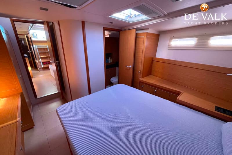 Een slaapkamer met een gestreept bed, houten kasten en een open deur naar een badkamer met toilet.