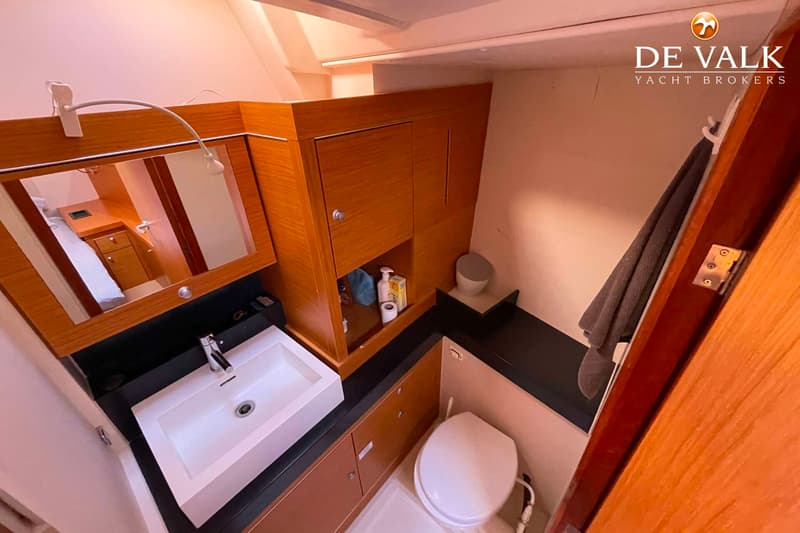 Een badkamer met een wastafel, spiegel, toilet, handdoek en opbergruimte.