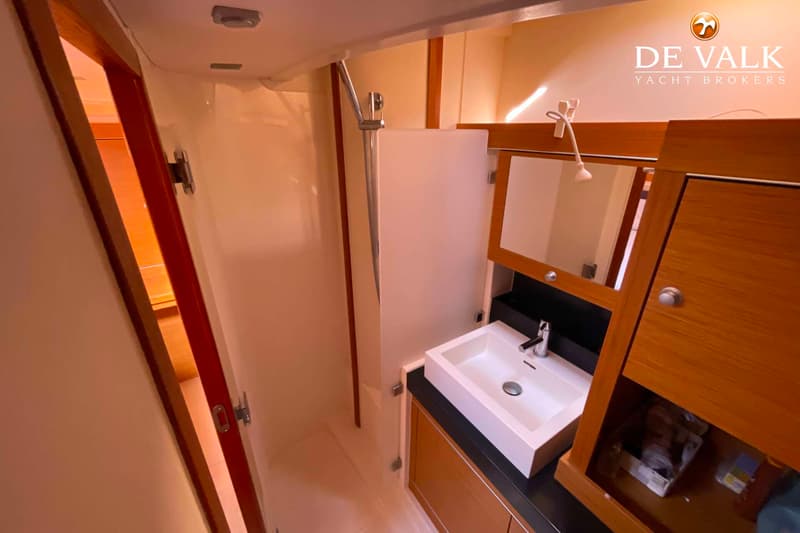 Een badkamer met een douchecabine, een wastafel met kraan en een spiegelkast.