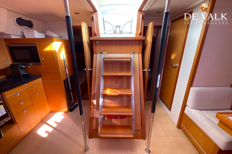 De foto toont het interieur van een boot met een houten trap, kombuis en zitbank. — Hanse 545