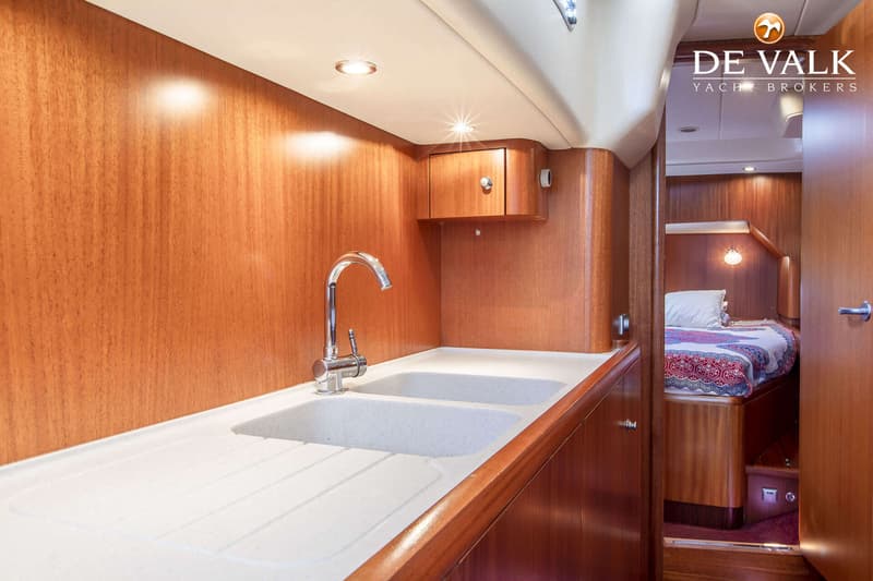 Een interieur van een boot met een aanrecht met dubbele spoelbak en kraan, en een doorkijk naar een slaapkamer. — Najad 570