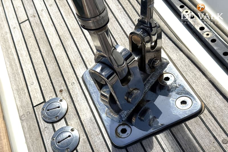 Een detailfoto van een teak dek met glimmende metalen beslag en twee ronde vuldoppen met "DIESEL" erop.