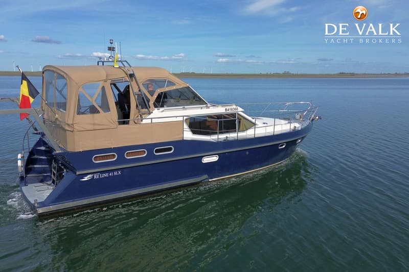 Een blauw-witte motorboot met een beige cabriokap vaart op rustig water onder een blauwe lucht met enkele wolken.