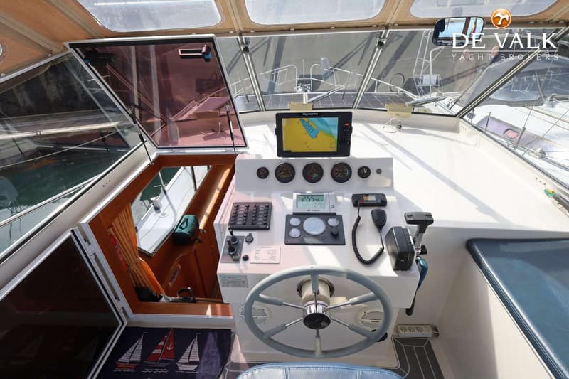 Een stuurstand met een Raymarine plotter, diverse meters, een stuurwiel en een marifoon.