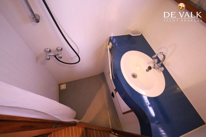 Een badkamer met een blauw aanrechtblad, een witte wasbak, een douchekop en een kraan.