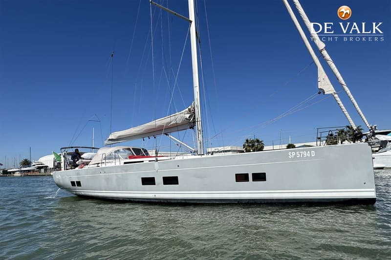 Een grijze zeilboot met witte strepen en de registratie "SP 5794 D" op de spiegel, ligt in het water. — Hanse 588