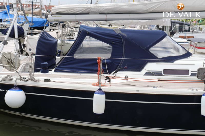 Een zeilboot met een donkerblauwe romp en een witte opbouw, voorzien van een blauwe buiskap en twee fenders. — Dehler 39 SQ