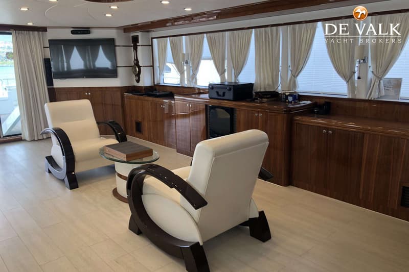 Een interieur van een boot met twee crèmekleurige fauteuils, een glazen salontafel, een tv en houten kasten. — BSY 98