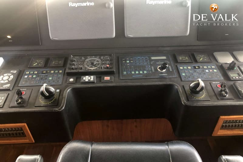 Een gedetailleerde foto van een stuurstand met diverse bedieningspanelen, joysticks en twee Raymarine schermen.