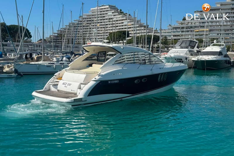 Een witte en donkerblauwe motorboot met de naam "NICE DAY" en registratienummer "NI E51965" vaart in een haven.
