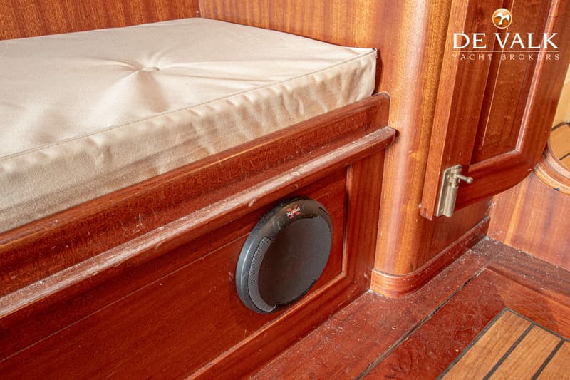 Een interieur van een boot met houten wanden en vloer, een beige kussen en een ingebouwde luidspreker. — Breedendam MTB 31