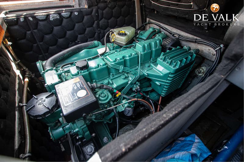 Een groene Volvo Penta scheepsmotor is zichtbaar in een motorruimte met zwarte geluidsisolatie.