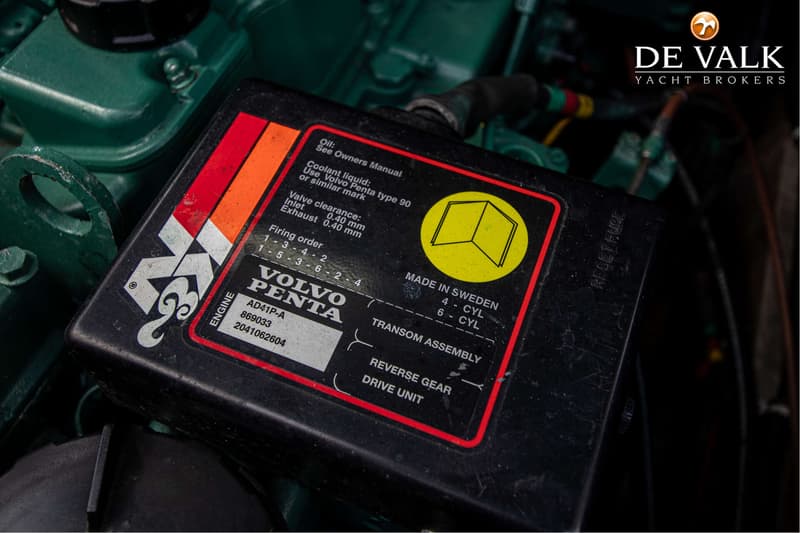 Een close-up van een zwarte sticker met witte en gele tekst en een rood-oranje streep, bevestigd op een groene motor.