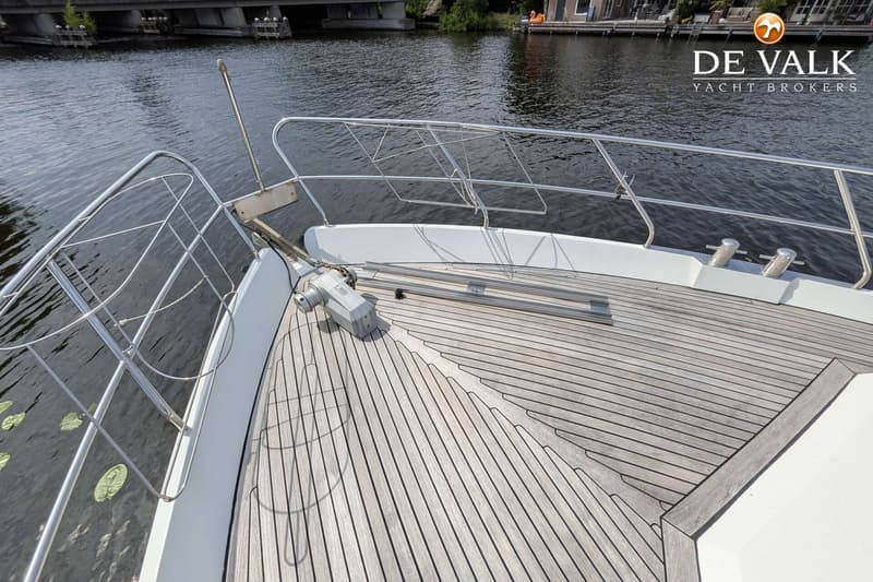De foto toont het voordek van een boot met een houten dek, reling en een ankerlier. — Van der Heijden Elegance 1500