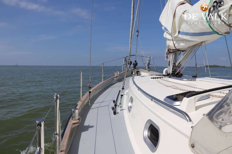 Een zeilboot vaart op open water met een opgerold zeil en een blauwe lucht. — Bornrif 33