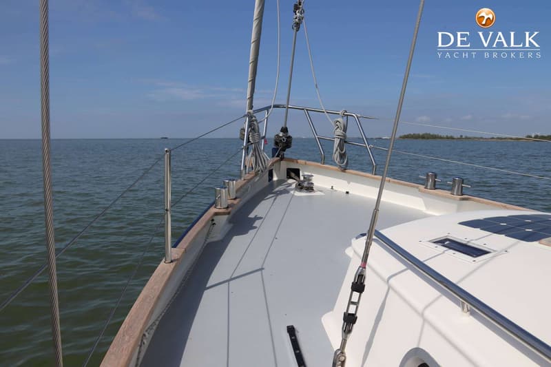 Een zeilboot op het water, gezien vanaf het voordek, met een mast, reling, en een zonnepaneel op de kajuit. — Bornrif 33