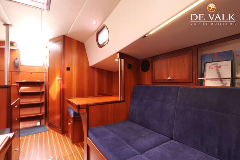 De foto toont het interieur van een boot met houten wanden en vloer, een blauwe bank en een tafel. — Bornrif 33