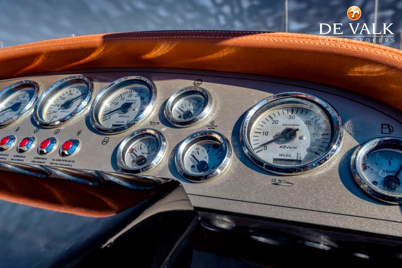 Een detailopname van een dashboard met diverse meters, knoppen en een oranje gestoffeerde rand.